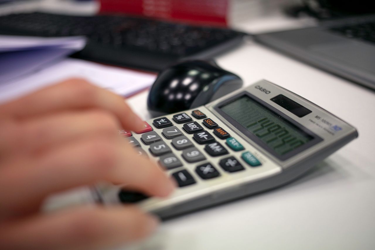 services-04 Close-up of a hand using a calculator on an office desk for accurate calculations.